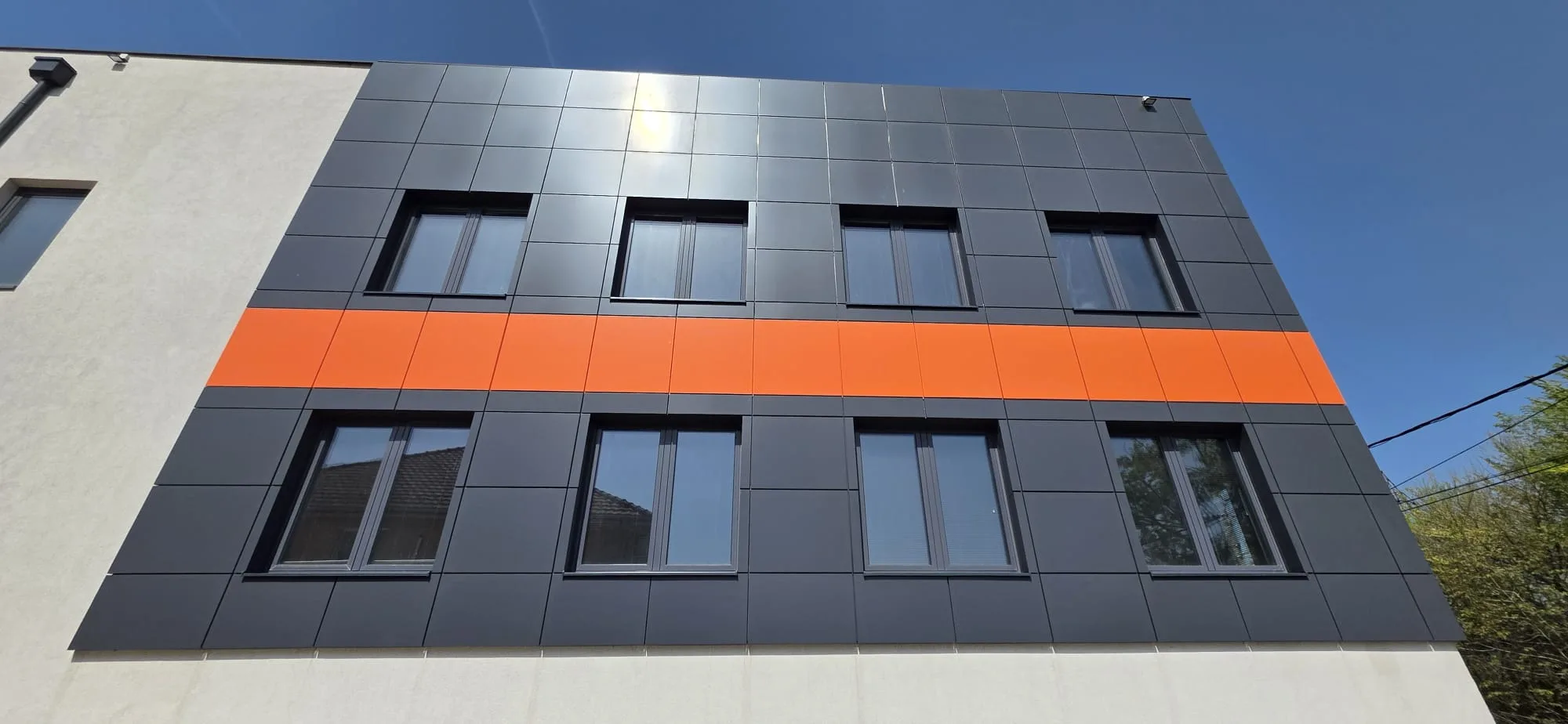 Ugaoni detalj završene ventilisane fasade sa kombinacijom tamnosive i narandžaste obloge